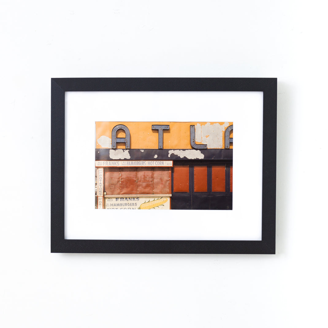 photo of a sign on a building framed in I-beam style black Williamsburg frame with a white mat