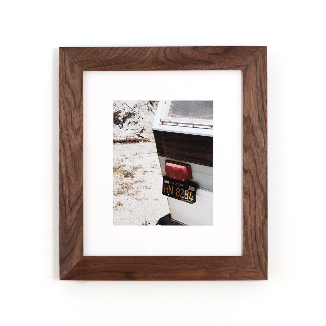 photograph of the license plate on the back of a camper framed in Walnut Wide hardwood frame style with white mat