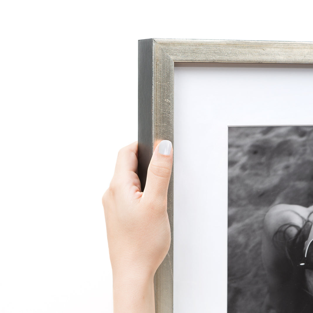 Top left corner of Black & white photo of a woman wearing sunglasses on the beach framed in a silver Beverly frame with white mat
