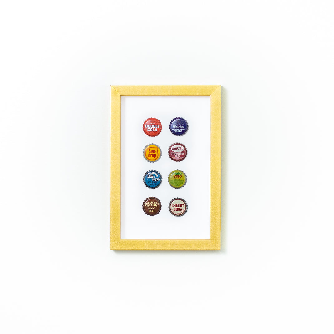eight bottle caps framed in modern gold Dolly frame