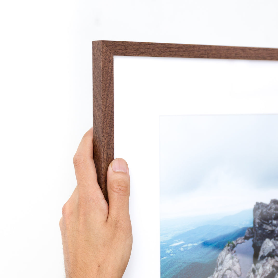 top left corner of landscape photo of mountains framed in mini Walnut hardwood frame style with a white mat