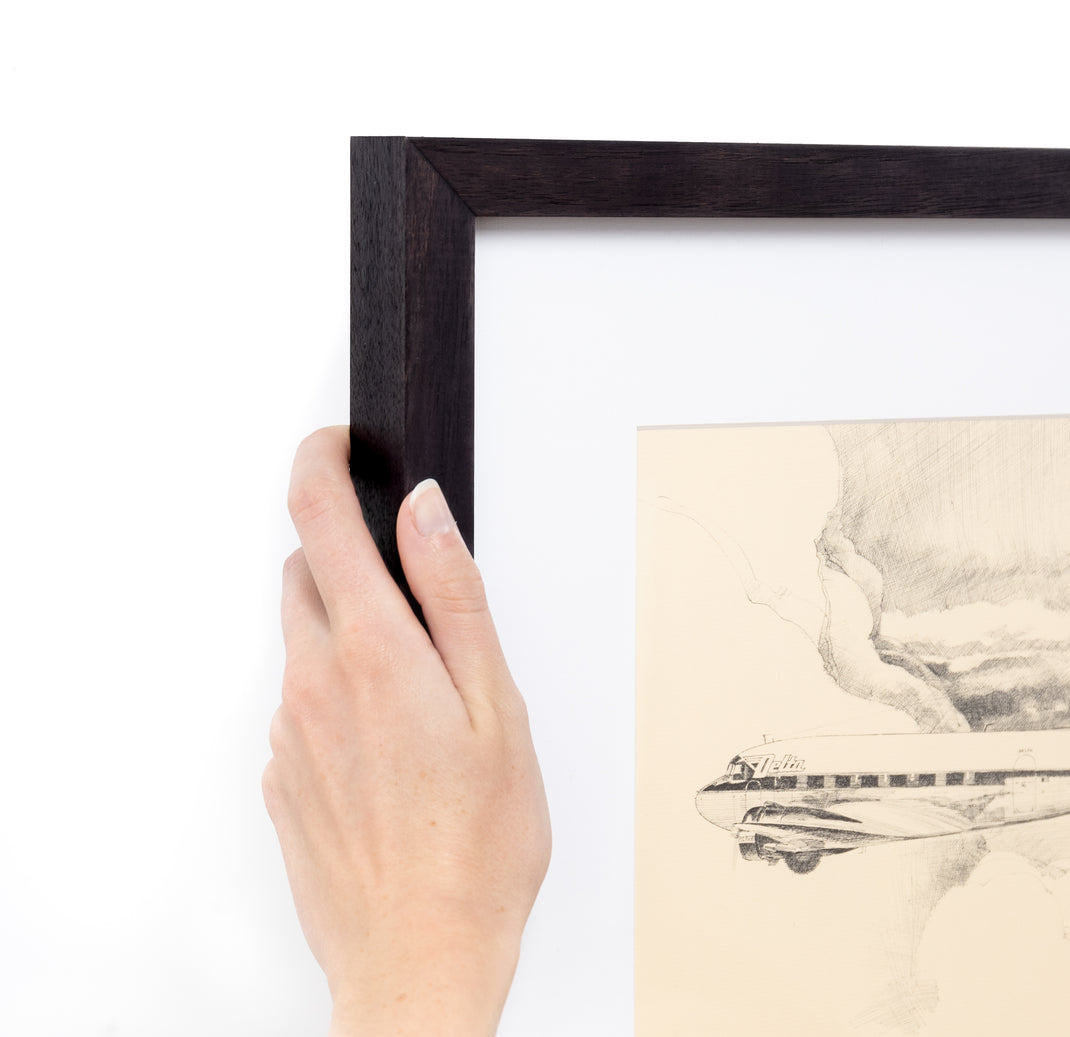 Top left corner of a Black and white sketch of an airplane framed in Black Walnut Gallery frame with a white mat