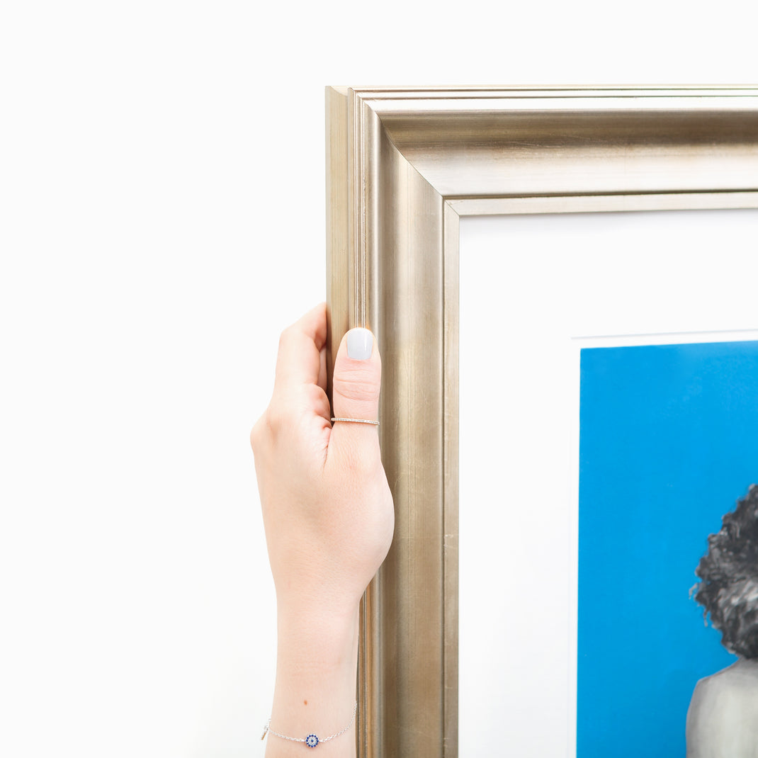 top left corner of art print of a woman's print on a blue background framed in bowery wide sloped silver frame