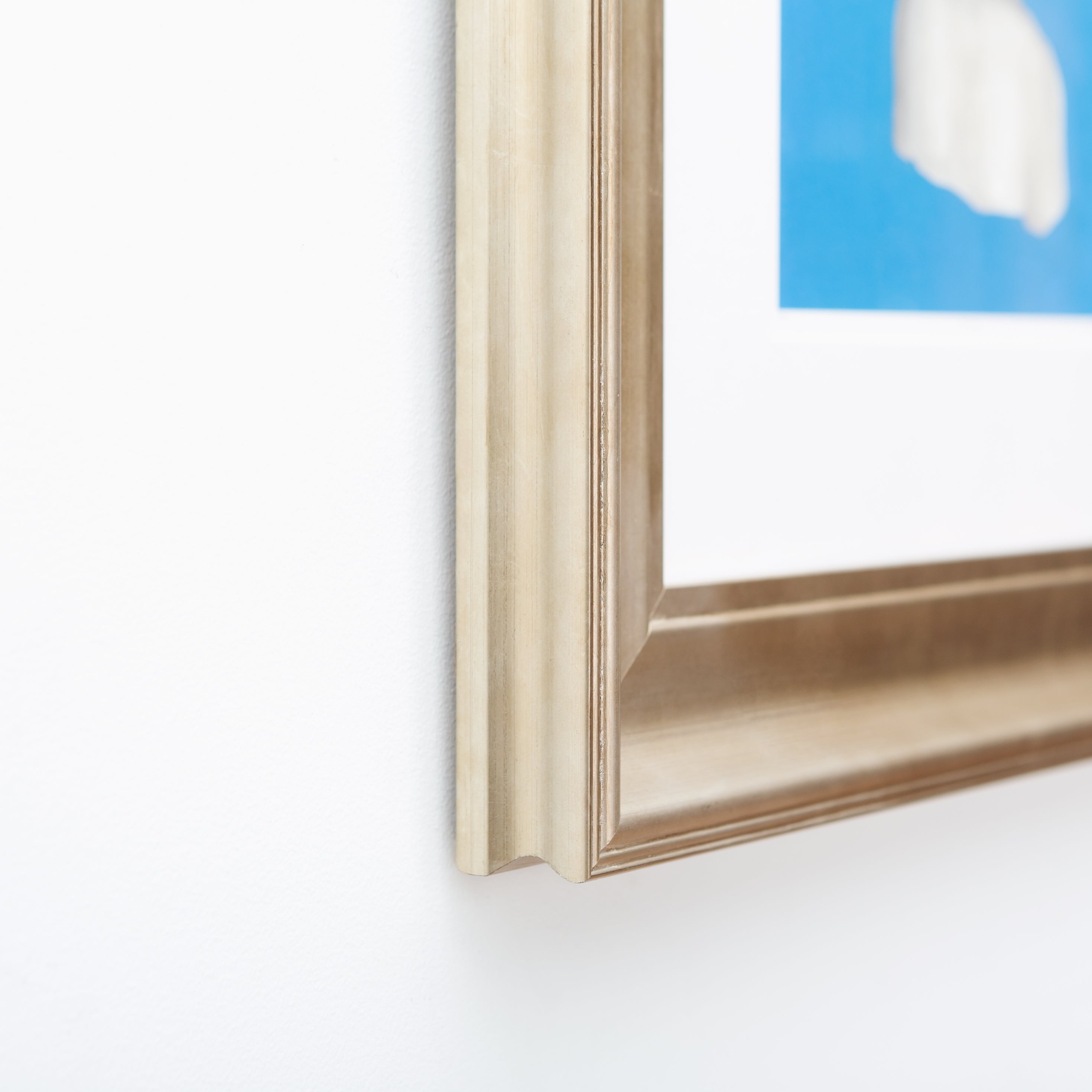 bottom left corner of an art print of a woman's print on a blue background framed in bowery wide sloped silver frame