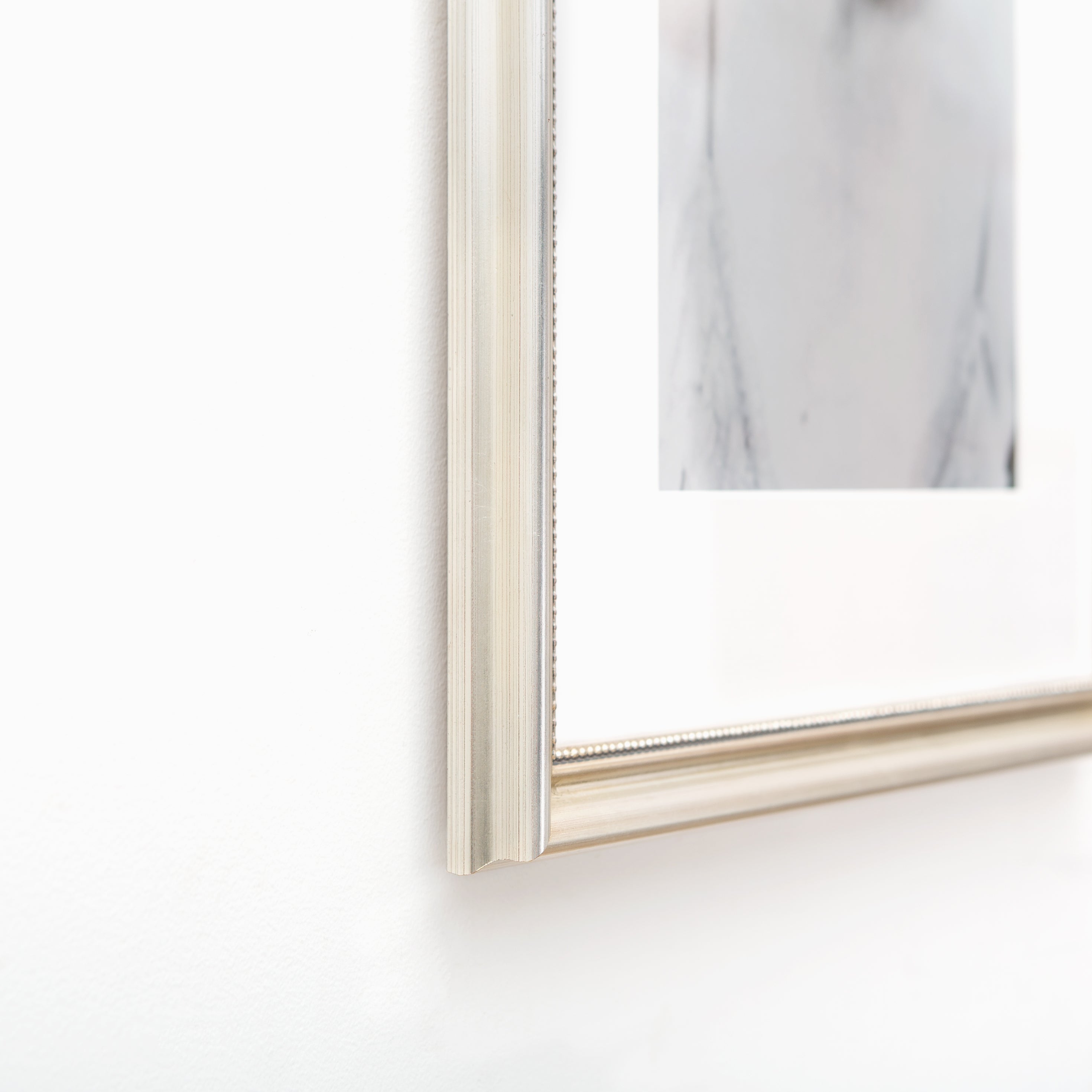 bottom left corner of black and white photo of a woman framed in Buckhead silver beaded frame with white mat