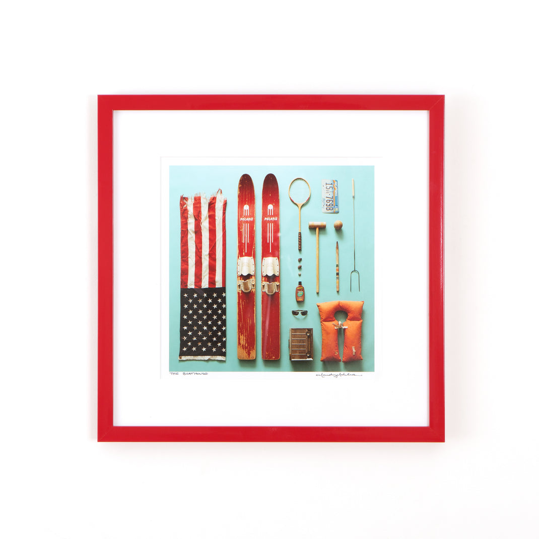 flat lay photograph of outdoor equipment framed in red lacquered Madrid frame with a white mat