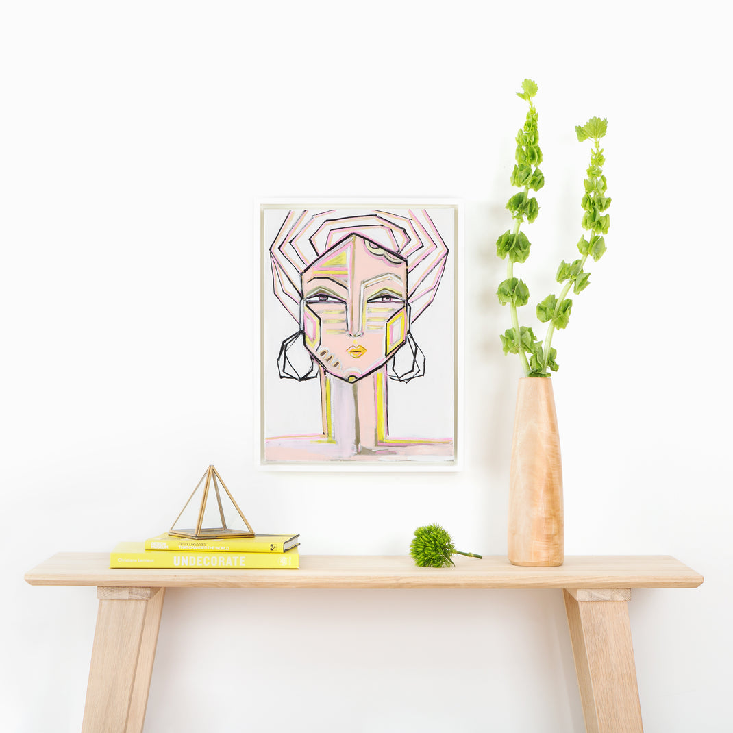 abstract portrait of a woman framed in white Palermo canvas floater frame hanging on a white wall above a wood console table